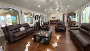 A spacious living room with leather sofas, a glass coffee table, and a cowhide rug. - NEW Hacienda Ranch W/ Resort Style Pool (Hempstead)