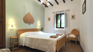A bedroom with a large bed, a chair, a window with curtains, and wall-mounted lights. - Castello di Montalto - Casa del Guardia (Castelnuovo Berardenga)