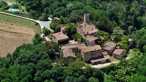 An aerial view of a historic castle complex with multiple buildings, surrounded by dense greenery. - Castello di Montalto - Casa del Guardia (Castelnuovo Berardenga)