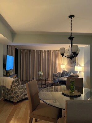 A modern living room with a flat-screen TV, a round glass table, and a sofa.