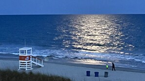 Una torre de salvavidas con el número 46, una playa y el océano bajo una luna brillante.
