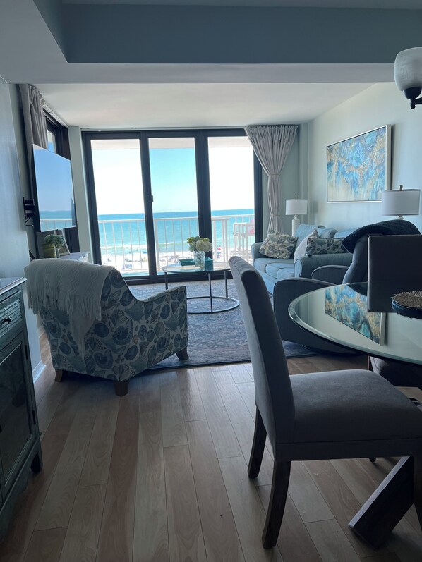 A living room with a view of the ocean, a sofa, a chair, a coffee table, and a TV. - Gorgeous, unobstructed direct oceanfront views!!! New floor to ceiling sliders! (North Myrtle Beach)