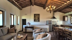 Un espacio habitable amplio con techo alto, una mesa de comedor y una cocina al fondo.