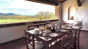 Mesa de desayuno lista con vista a un paisaje verde y montañas.