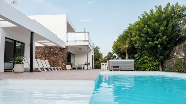 A modern house with a swimming pool, a patio with chairs, and a stone wall. - Fully equipped villa for 6 to 8 people located in Lajares (Lajares)