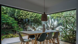 A dining area with a wooden table and chairs, large windows, and a hanging light fixture. - Fully equipped villa for 6 to 8 people located in Lajares (Lajares)