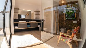 A modern bathroom with a glass partition, wooden vanity, and a colorful chair. - Fully equipped villa for 6 to 8 people located in Lajares (Lajares)