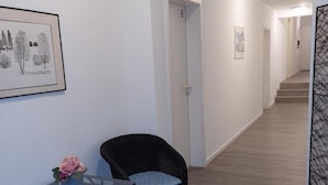 A hallway with a glass table and chairs, a framed picture on the wall, and a door marked with the number 8.