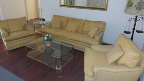 A living room with a sofa set, a coffee table, a lamp, and a framed mirror on the wall.