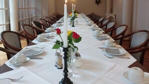 A long dining table set for a meal with candles, flowers, and tableware.