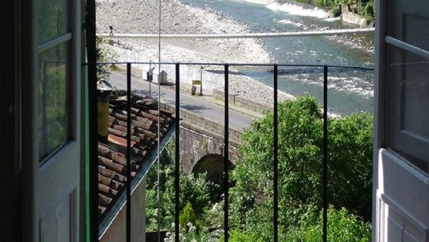 Uitzicht vanuit een raam op een rivier, een brug en een heuvel met gebouwen.