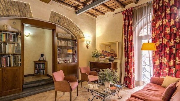 A cozy living room with a sofa, armchairs, a coffee table, and bookshelves. - Hotel Residenza San Calisto (Rome)