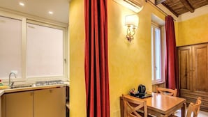 A kitchen with a dining area, featuring a stove, sink, and wooden cabinets. - Hotel Residenza San Calisto (Rome)