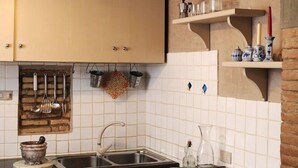 A kitchen with wooden cabinets, a brick wall, and a hanging pot rack. - Hotel Residenza San Calisto (Rome)