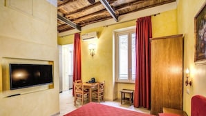 A bedroom with a bed, a TV mounted on the wall, a wooden door, and a window with curtains. - Hotel Residenza San Calisto (Rome)
