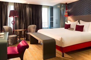 Una habitación de hotel moderna con una cama grande, un escritorio, una silla, una mesita y un banco.