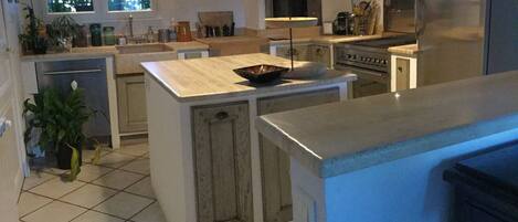 Een moderne keuken met een centraal eiland, inbouwapparatuur en veel werkruimte.