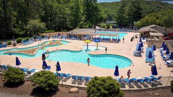A pool area with multiple swimming pools, lounge chairs, and umbrellas.