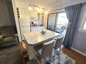 A compact kitchen with a dining area, a sofa, and a view of the outdoors. - Apple Valley 3 at Rumbling Bald (Lake Lure)