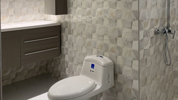 Un baño de diseño moderno, con inodoro, espejo y zona de ducha con puerta de cristal.