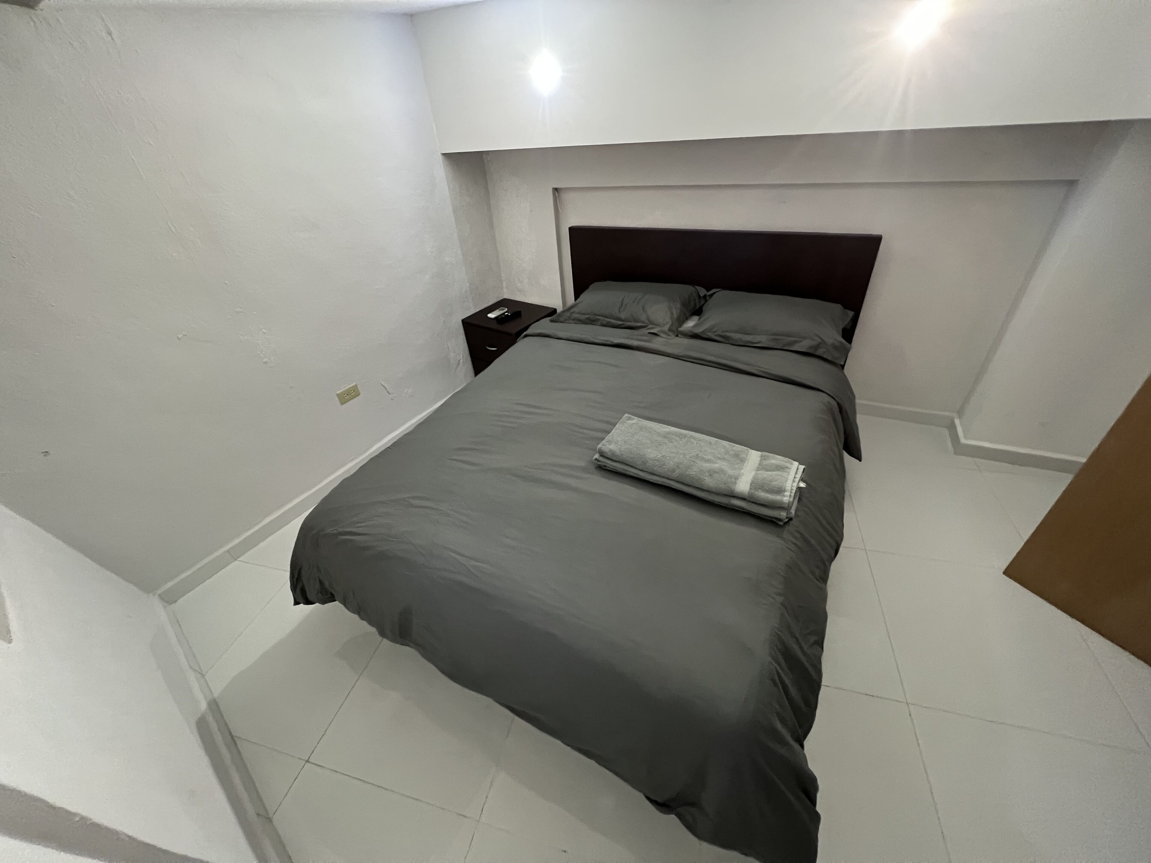 A bedroom with a bed, a nightstand, and a headboard.