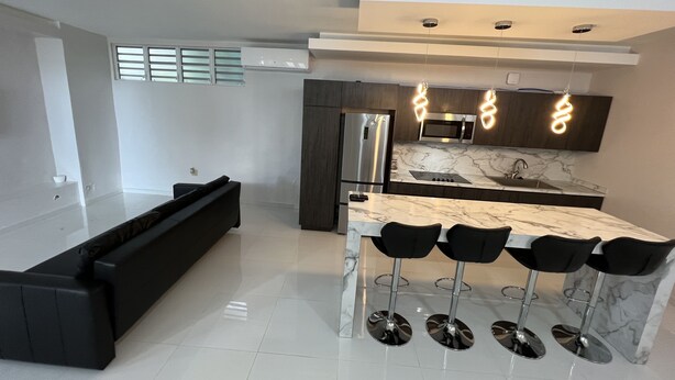 Una cocina moderna con encimera de mármol, electrodomésticos de acero inoxidable y una zona de bar con taburetes.