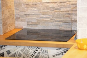A kitchen with a stone backsplash and a wooden countertop. - Marci's Home (Roma)