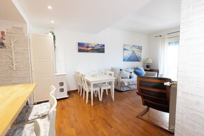 A modern living room with a wooden dining table, white chairs, a sofa, and a radiator. - Marci's Home (Roma)