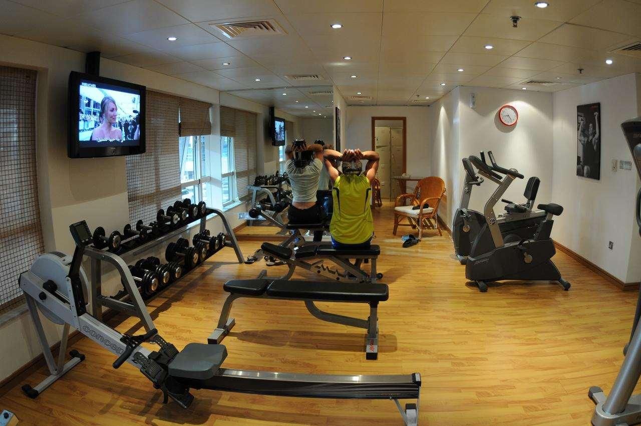 Un gimnàs amb màquines cardiovasculars, peses i una pantalla de televisió.