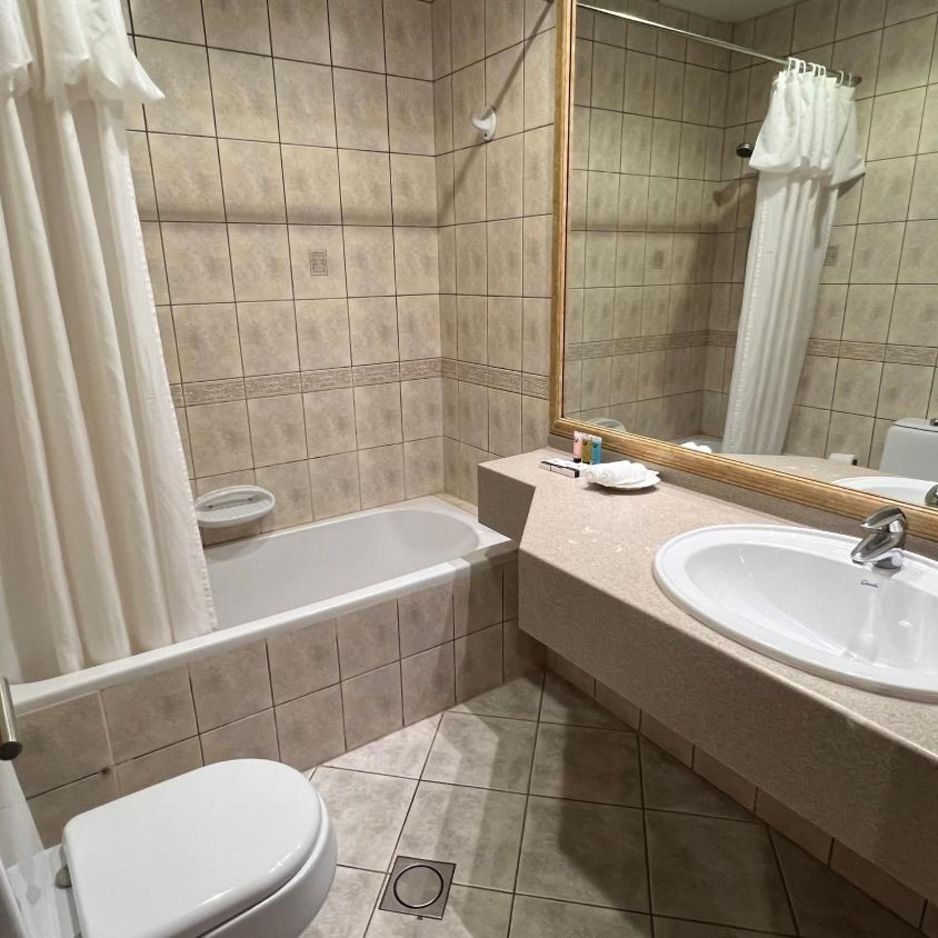 A bathroom with a bathtub, toilet, and two sinks.