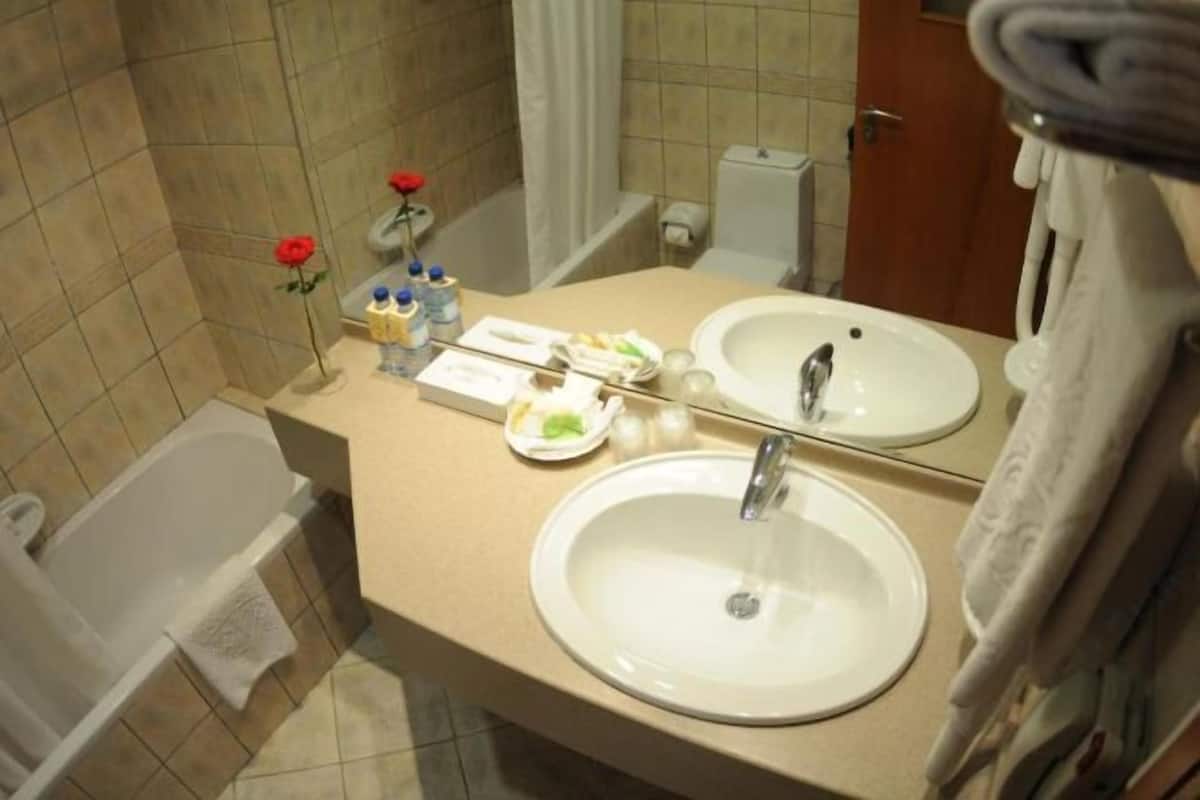 Une salle de bain avec une baignoire, deux lavabos, un miroir et des articles de toilette posés sur le comptoir.