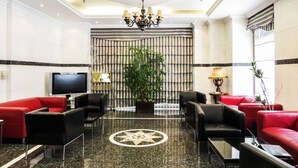 A lobby with a television, red and black sofas, a chandelier, and a large plant. - The Uptown Apartments Abu Dhabi by Gewan (Abu Dhabi)