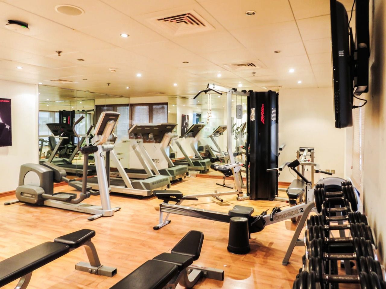 Ein Fitnessstudio mit Laufbändern, Crosstrainern und Gewichtsbänken.