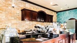 A kitchen area with a stone wall, wooden cabinets, and a coffee station. - The Uptown Apartments Abu Dhabi by Gewan (Abu Dhabi)
