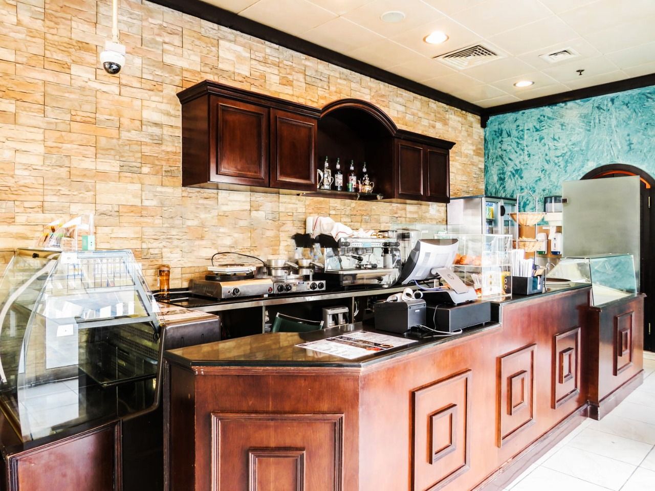 A kitchen area with a stone wall, wooden cabinets, and a coffee station.