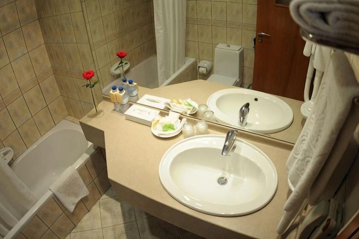 Un baño con bañera, dos lavamanos, un espejo y artículos de aseo.