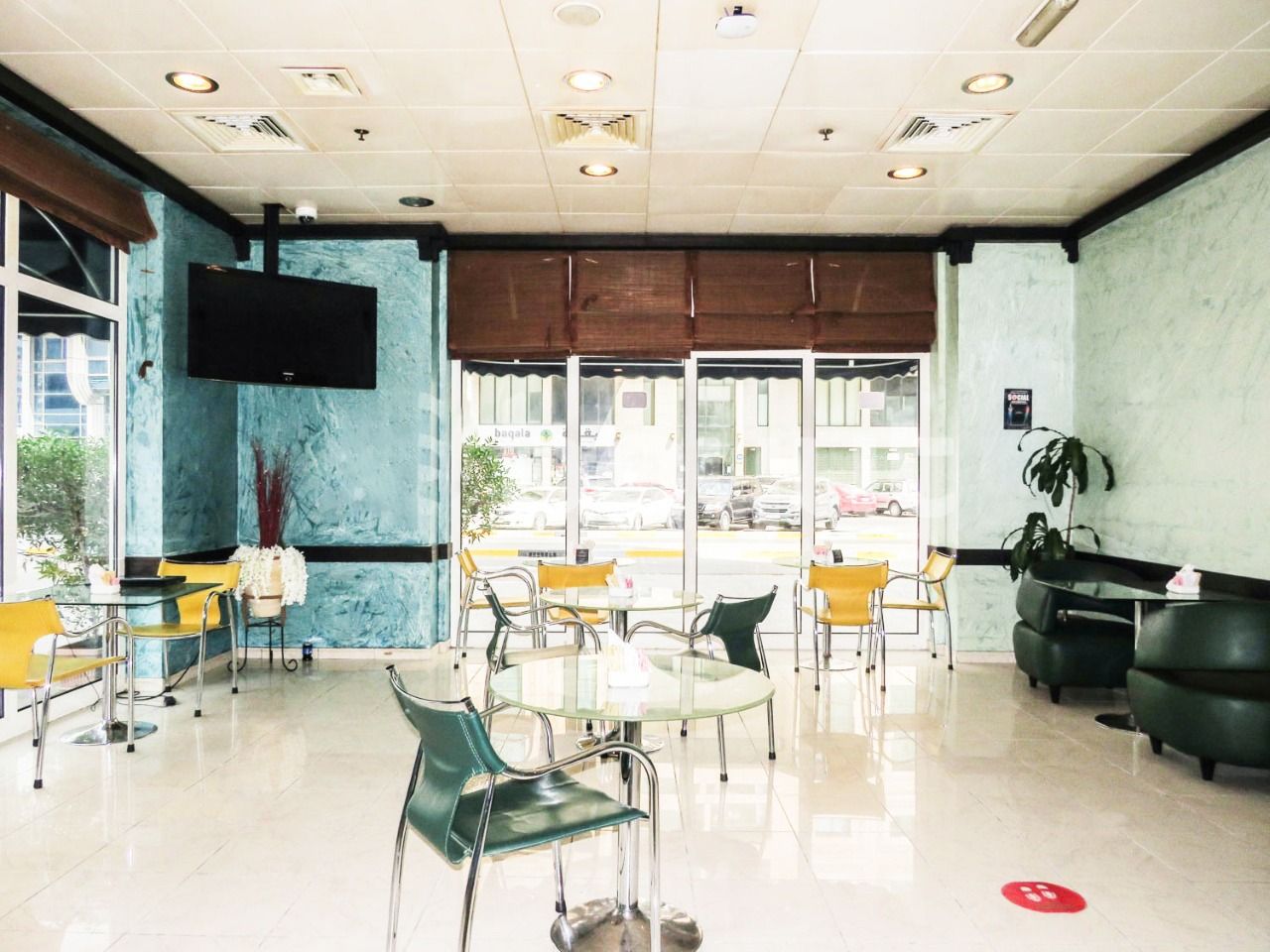 A hotel lobby with a large TV, multiple seating areas, and a view of the street outside.