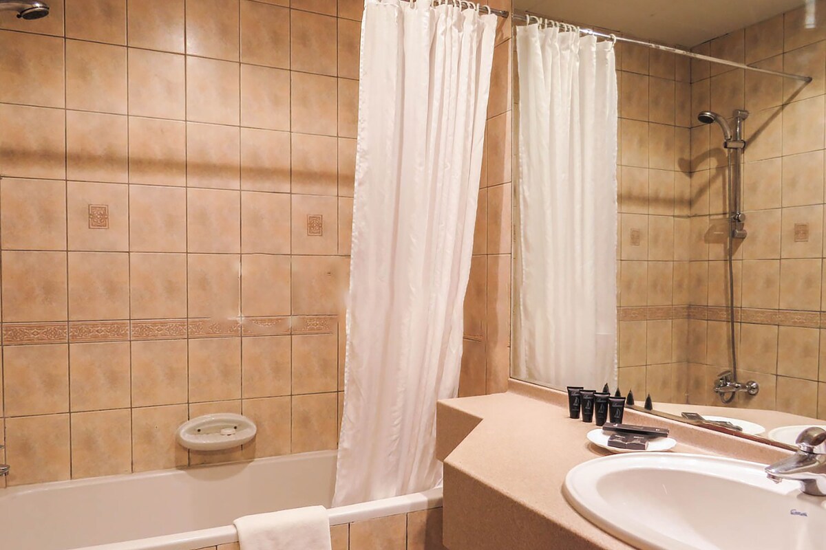 Een badkamer met een bad, douche, wastafel en spiegel.