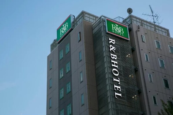 Experience the sleek, grid-like facade of the R&B Hotel, featuring a prominent sign and evenly spaced windows.
