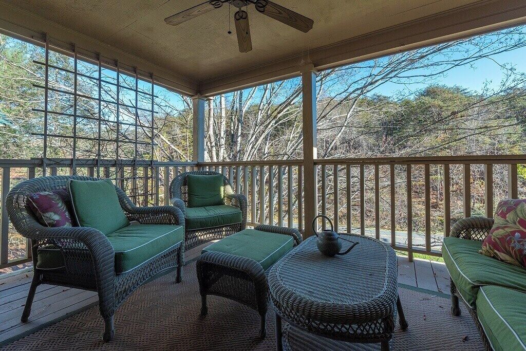 A covered outdoor seating area with wicker furniture and a ceiling fan.