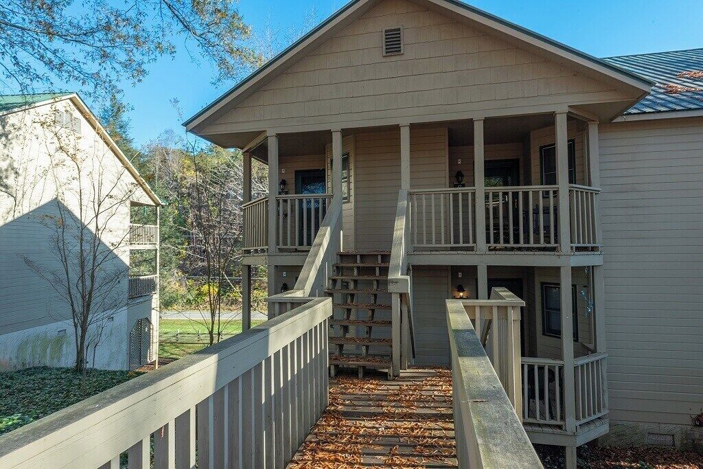 A two-story building with a balcony, a staircase leading to the upper floor, and a fenced area.