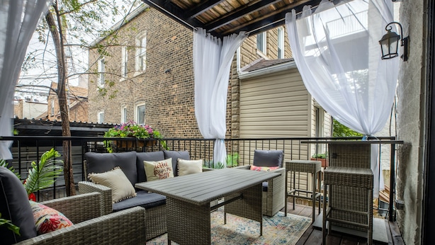 An outdoor patio with wicker furniture, a table, and a cushioned sofa.