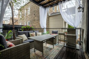 An outdoor patio with wicker furniture, a table, and a cushioned sofa. - NEW LUXURY CONDO WITH PATIO DECK (Chicago)