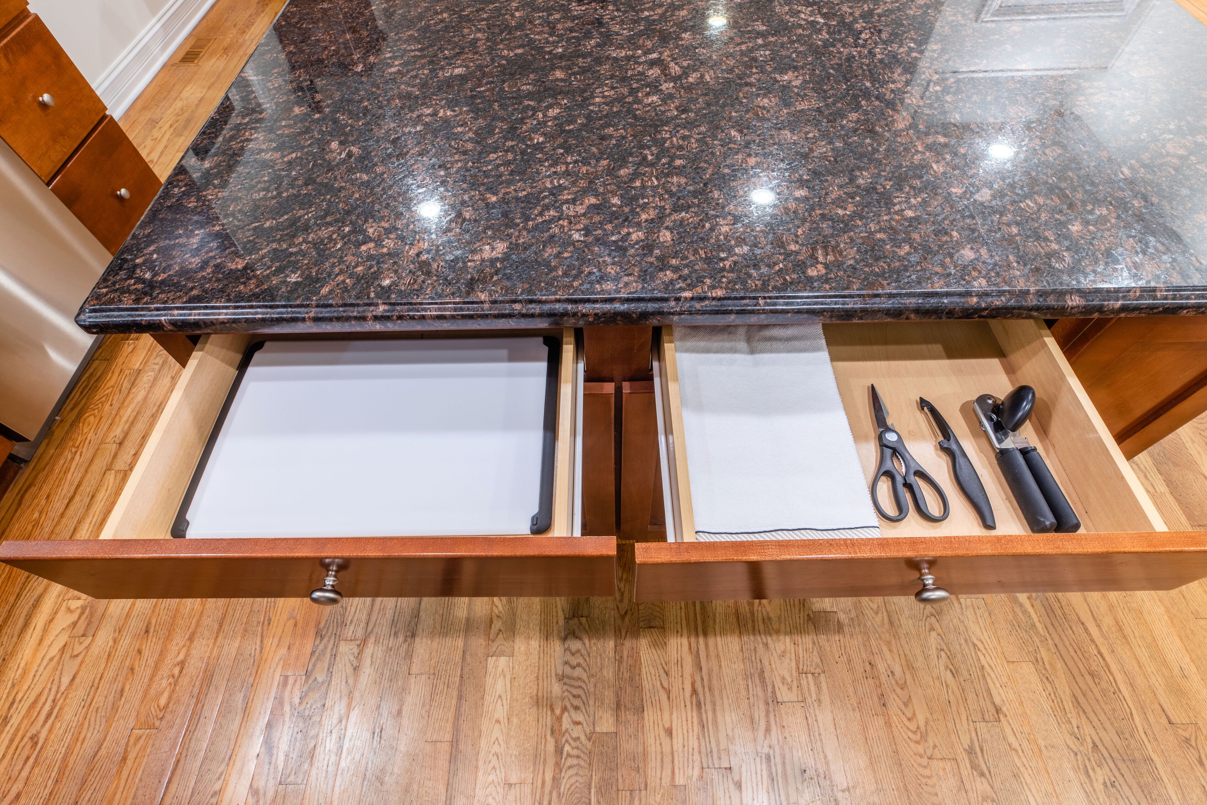 A kitchen with a granite countertop and two drawers below.