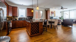 A spacious kitchen with wooden cabinets, a central island, and a dining area with chairs and a table.