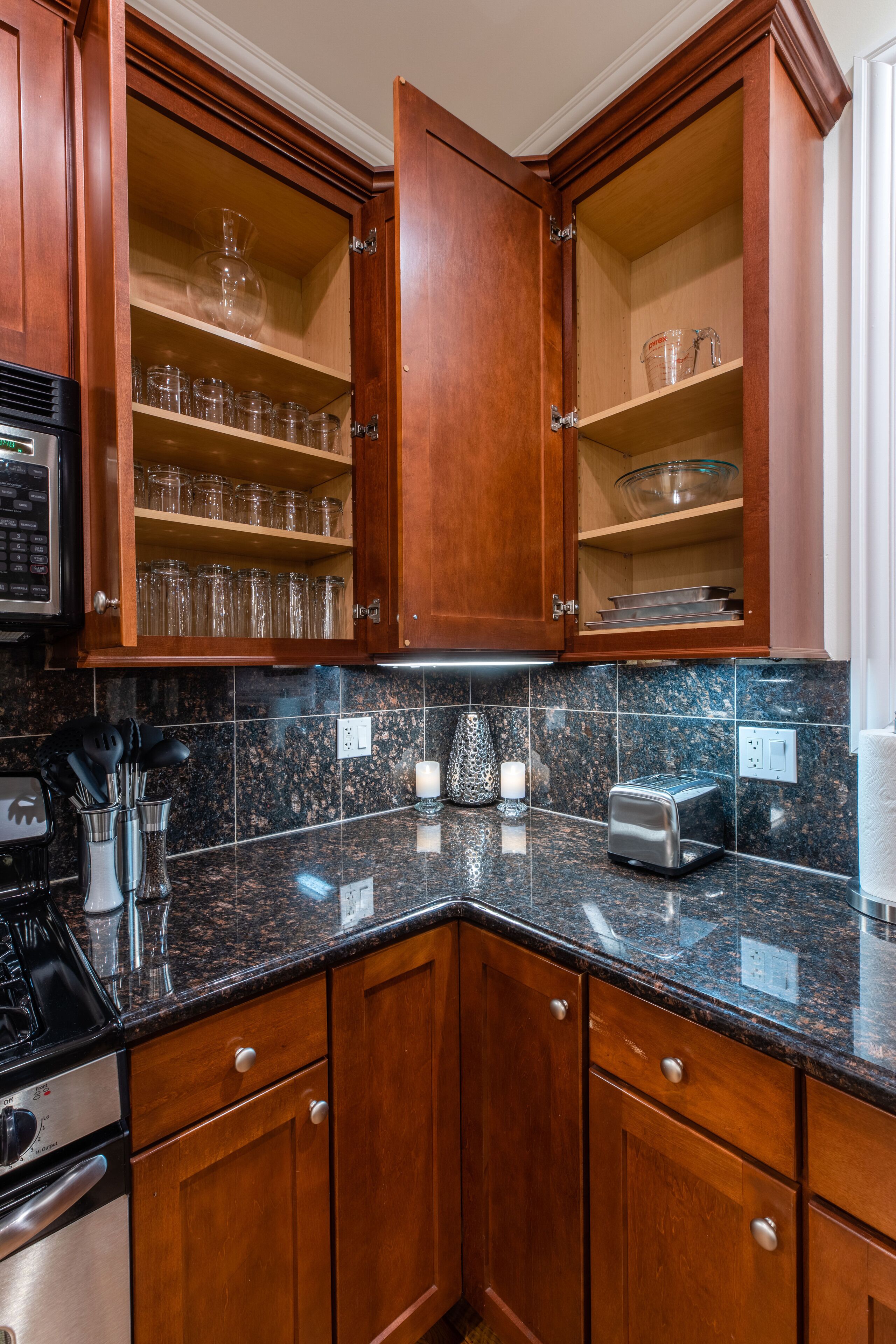 A kitchen with wooden cabinets, granite countertops, a toaster, and a microwave.