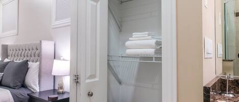 Ein Schlafzimmer mit Bett, Nachttisch und Kleiderschrank mit Regalen und Wäschekorb.