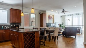 A spacious kitchen with wooden cabinets, a central island, and pendant lighting.