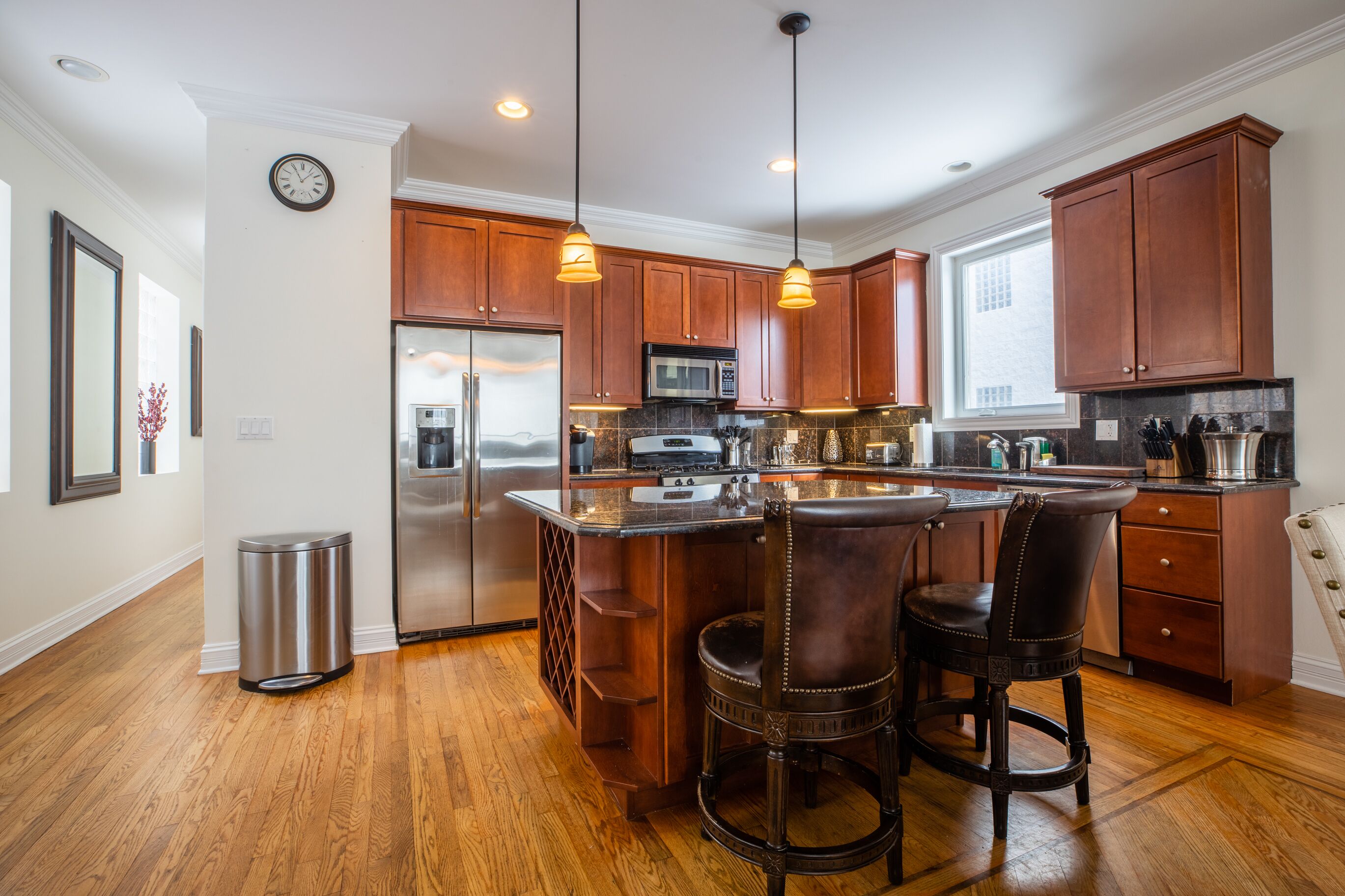 Una cocina moderna con armarios de madera, electrodomésticos de acero inoxidable y una isla central con taburetes de bar.