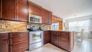 A kitchen with wooden cabinets, a built-in oven, a microwave, and a stone backsplash.